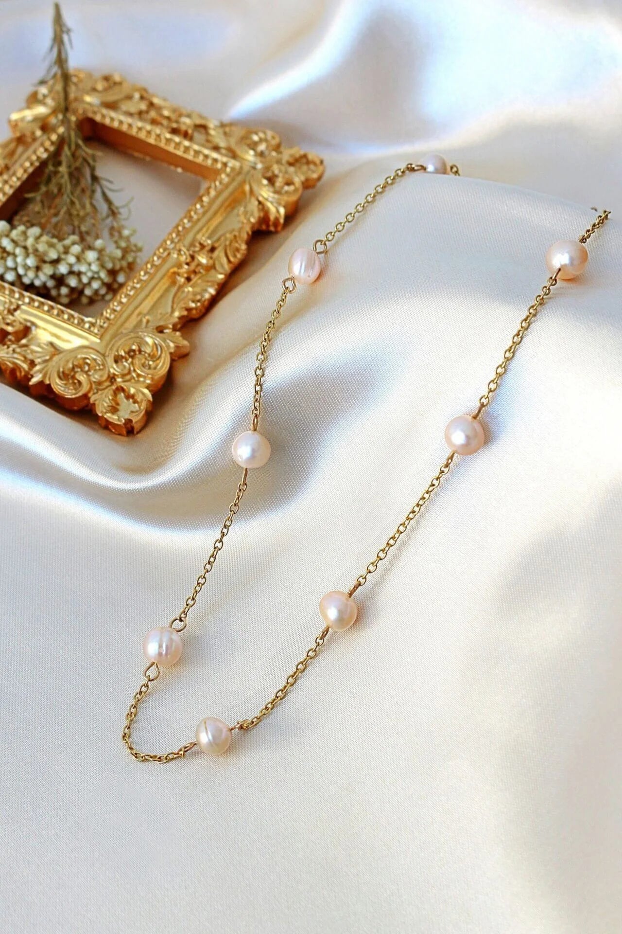 Gold necklace with pearls on a white fabric background