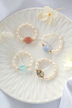 Three pearl bracelets with colorful beads on a white plate with flowers.