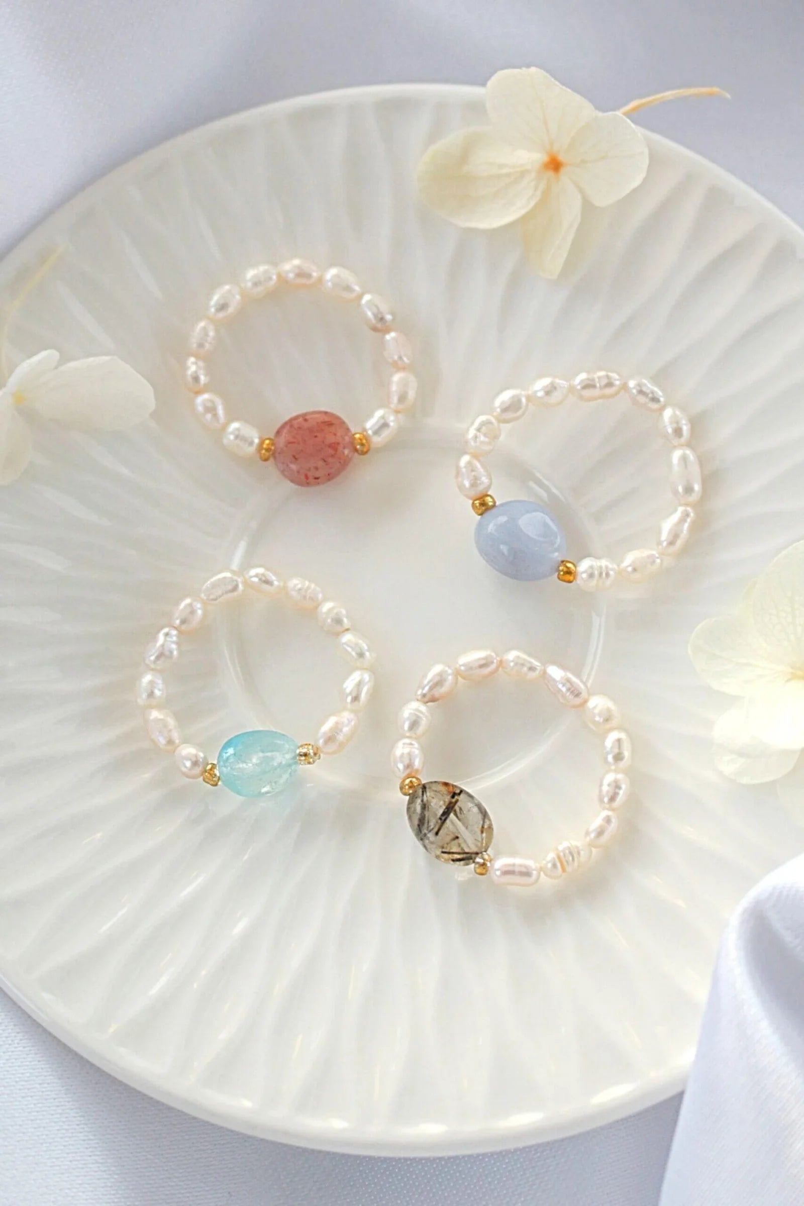 Three pearl bracelets with colorful beads on a white plate with flowers.
