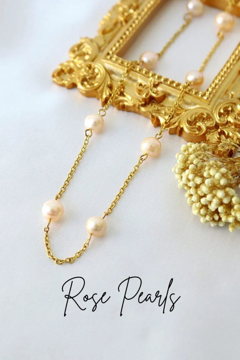 Gold necklace with rose pearls on a white background