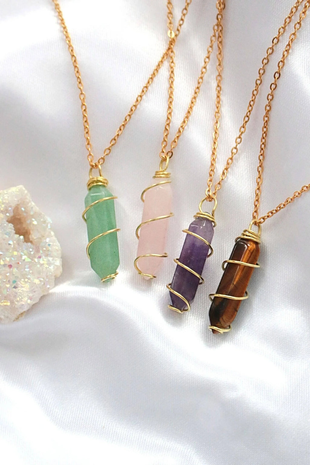Four gold necklaces with different colored gemstone pendants on a white background