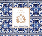 "Casa Amalfi Blue Maiolica Gift Box with two vegan body soaps—Blue Grotto Acqua Marine and Sunset in Procida Honey & Vanilla—and one Ischia Water Jasmine & Chamomile body scrub soap, plus a hand-painted ceramic soap dish from Vietri Sul Mare, all inspired by the Amalfi Coast and beautifully presented in a blue maiolica design."
