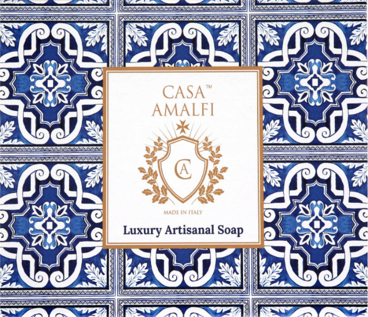 "Casa Amalfi Blue Maiolica Gift Box with two vegan body soaps—Blue Grotto Acqua Marine and Sunset in Procida Honey & Vanilla—and one Ischia Water Jasmine & Chamomile body scrub soap, plus a hand-painted ceramic soap dish from Vietri Sul Mare, all inspired by the Amalfi Coast and beautifully presented in a blue maiolica design."