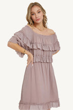 "Mystic mauve off-shoulder bohemian dress with short sleeves, elastic waist, and ruffle bottom, offering a relaxed fit and feminine silhouette."