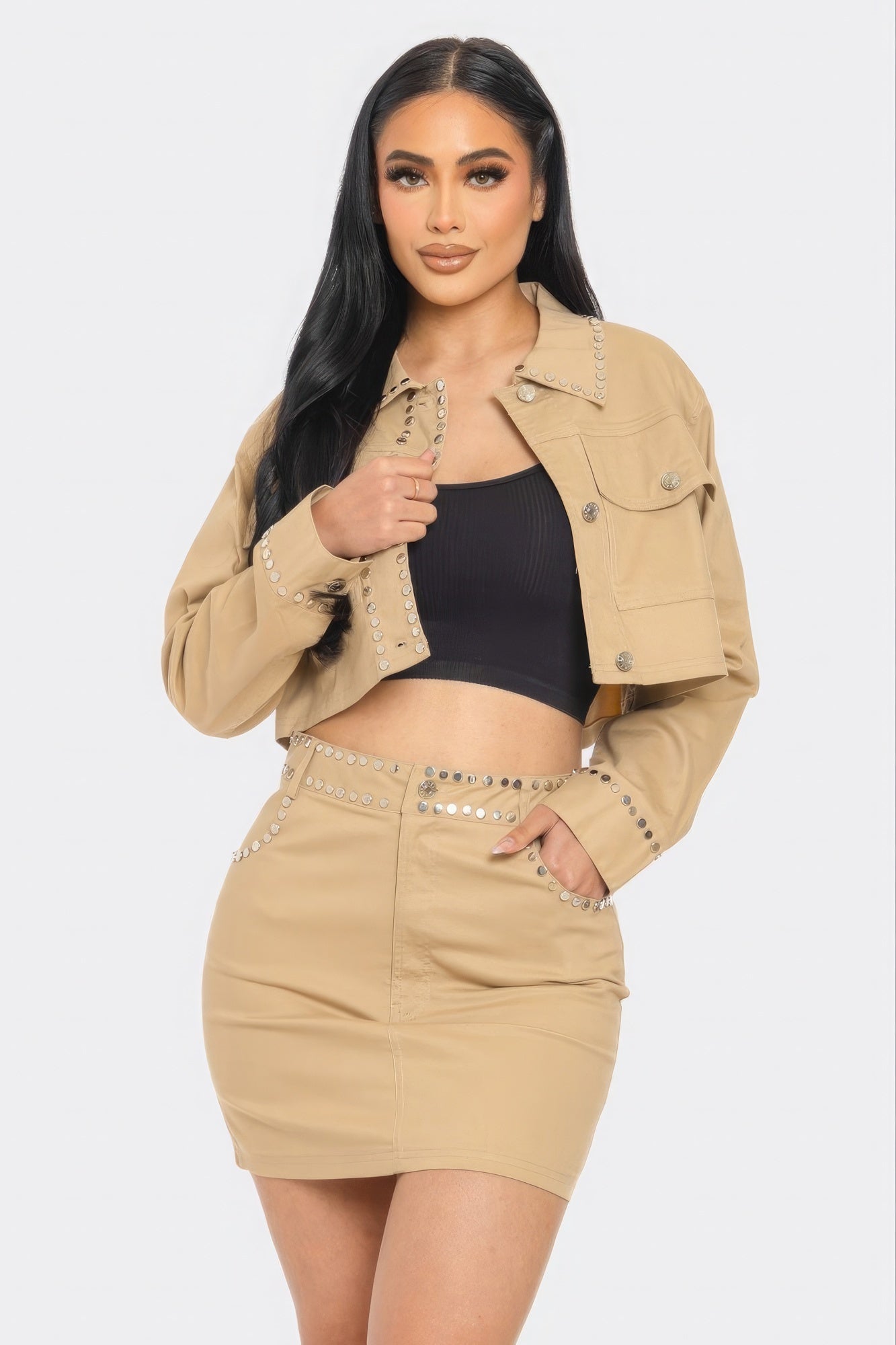 Woman wearing a beige jacket and skirt set with a black top on a white background