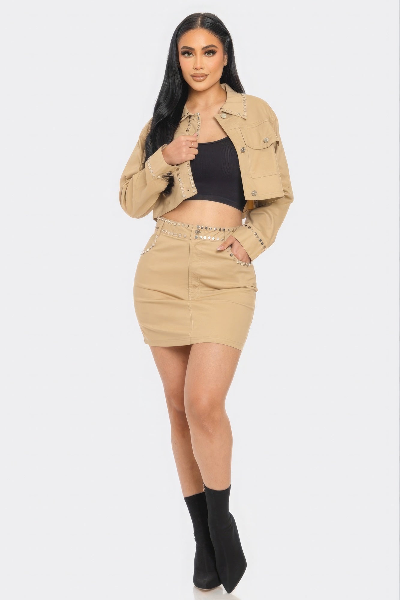 Woman wearing a beige jacket and skirt with black top on a white background