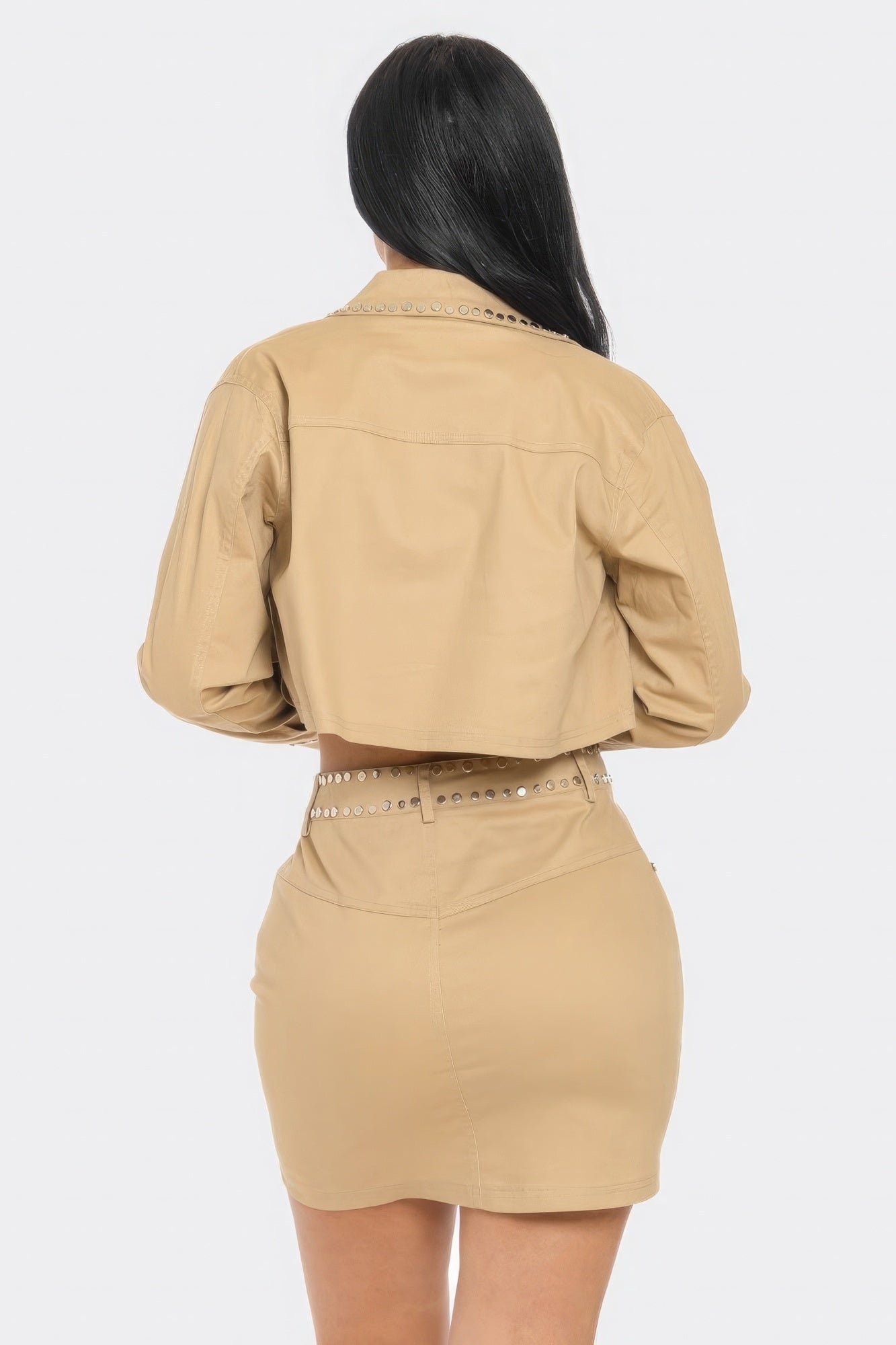Person wearing a beige two-piece outfit with a jacket and skirt on a white background