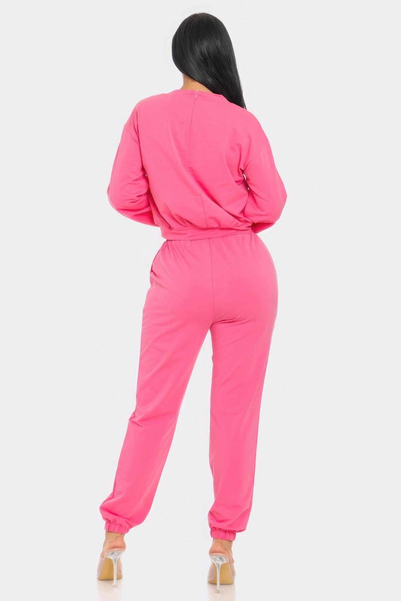 Person wearing a bright pink tracksuit on a white background