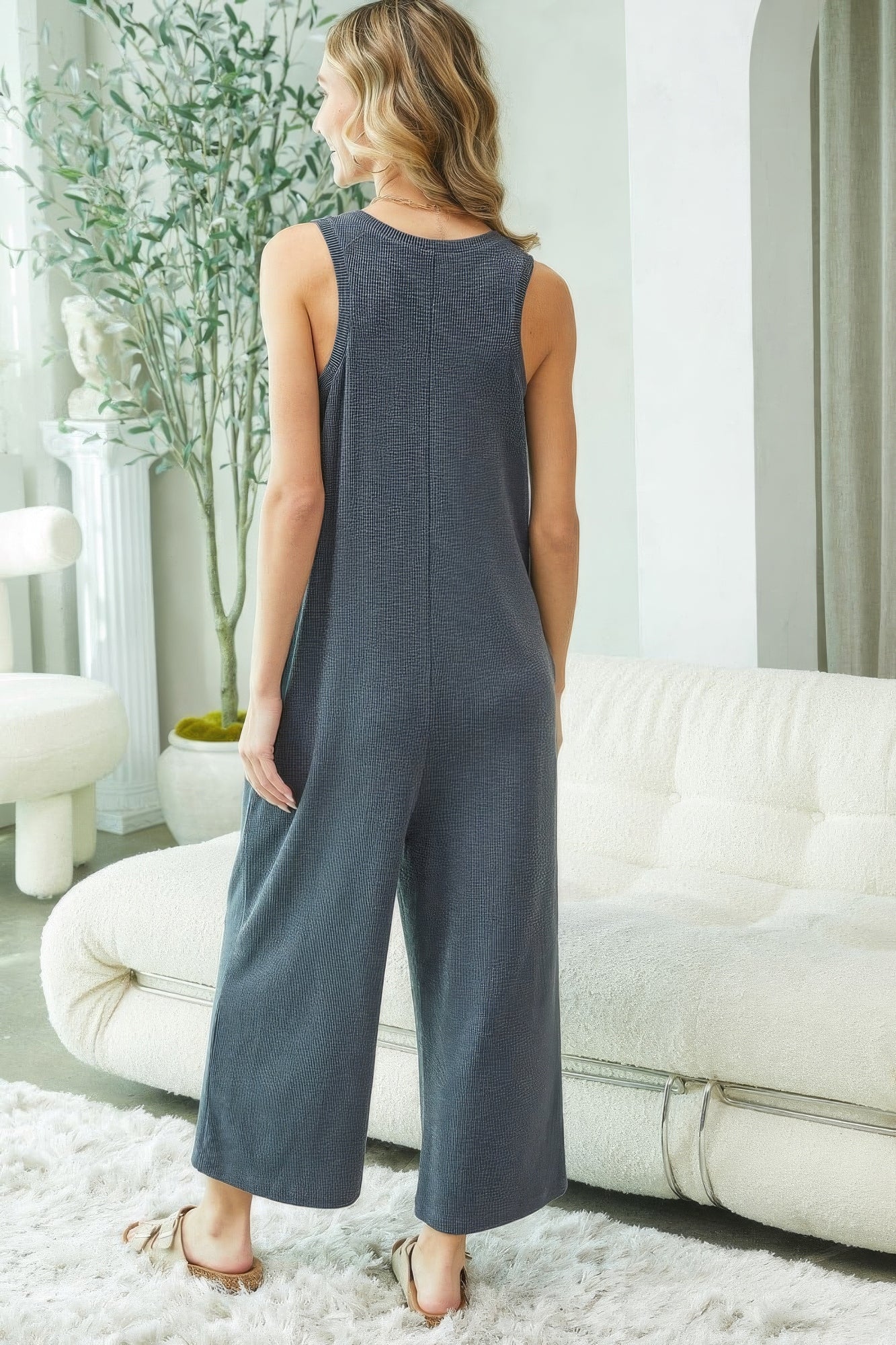 Woman wearing a blue jumpsuit in a living room setting