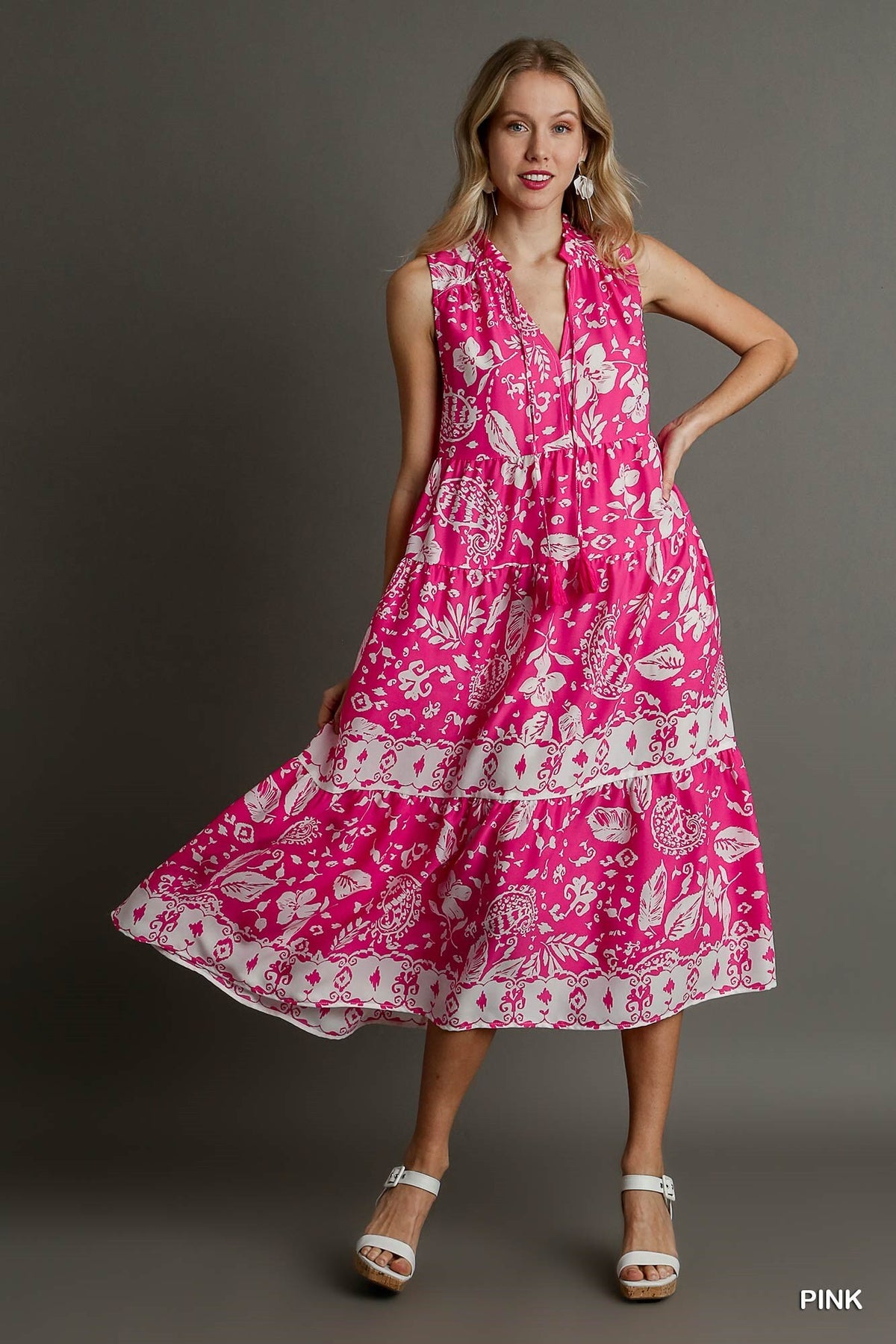Woman wearing a pink dress with white floral pattern on a gray background