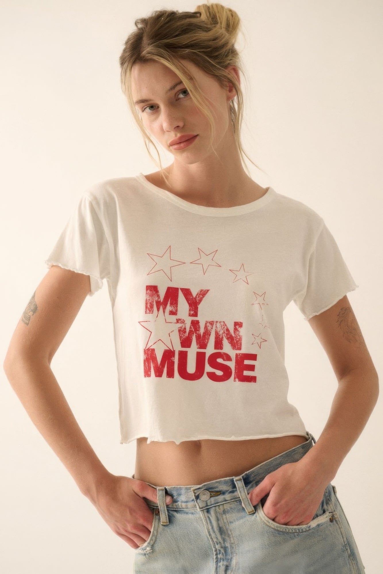 Woman wearing a white t-shirt with red text and stars on a plain background