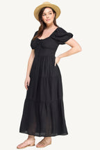 Plus-size black tiered maxi dress with front tie, puff sleeves, and flowing silhouette. Lightweight polyester fabric for breathable, elegant comfort and style.