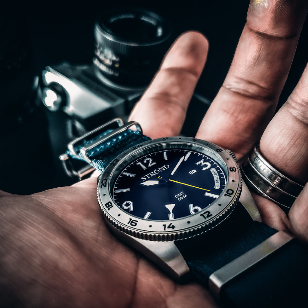 Close-up of a person wearing a Strongo watch with a dark background