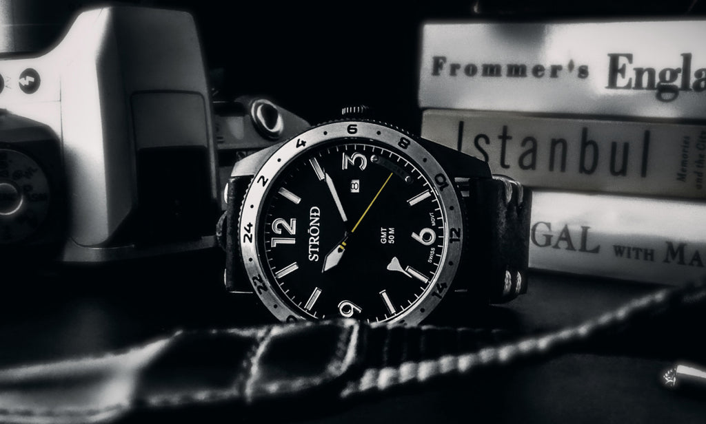 Stuhrling watch on a textured surface with books in the background