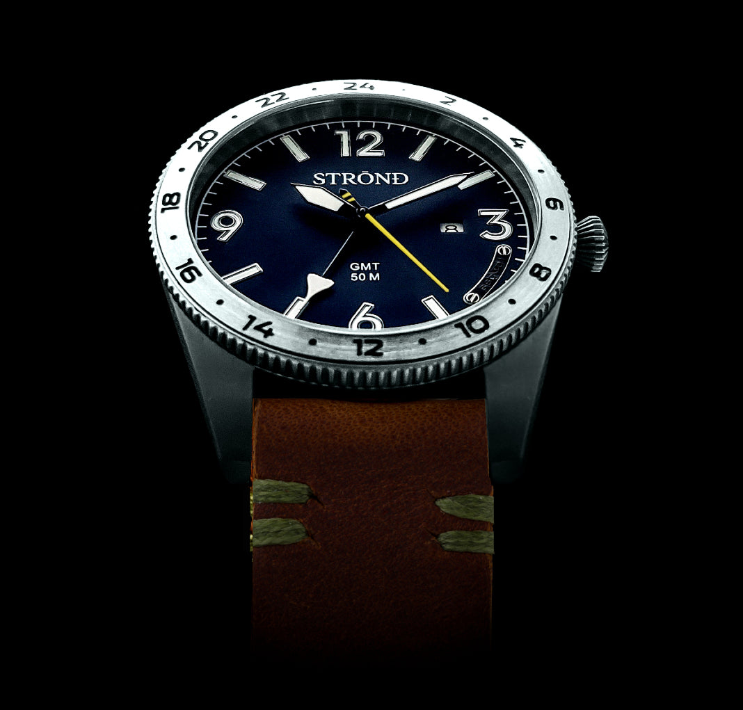 Watch with a dark blue face and brown strap on a black background