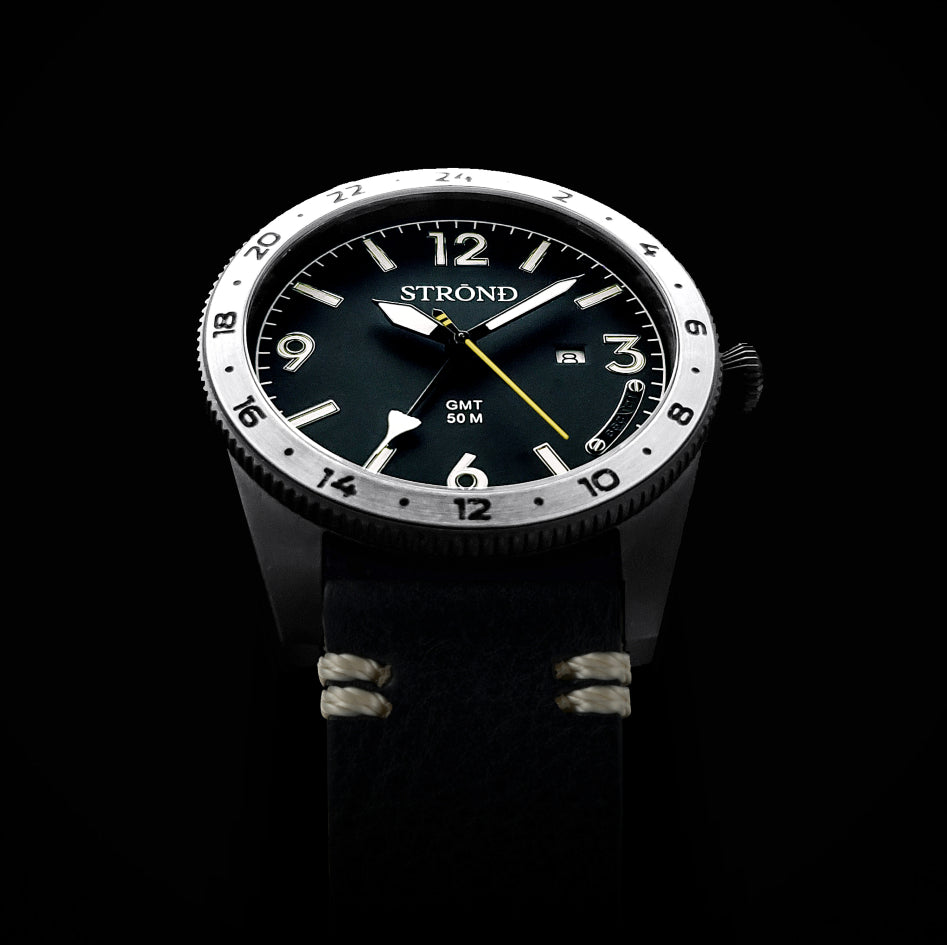 Watch with black face and silver case on a black background