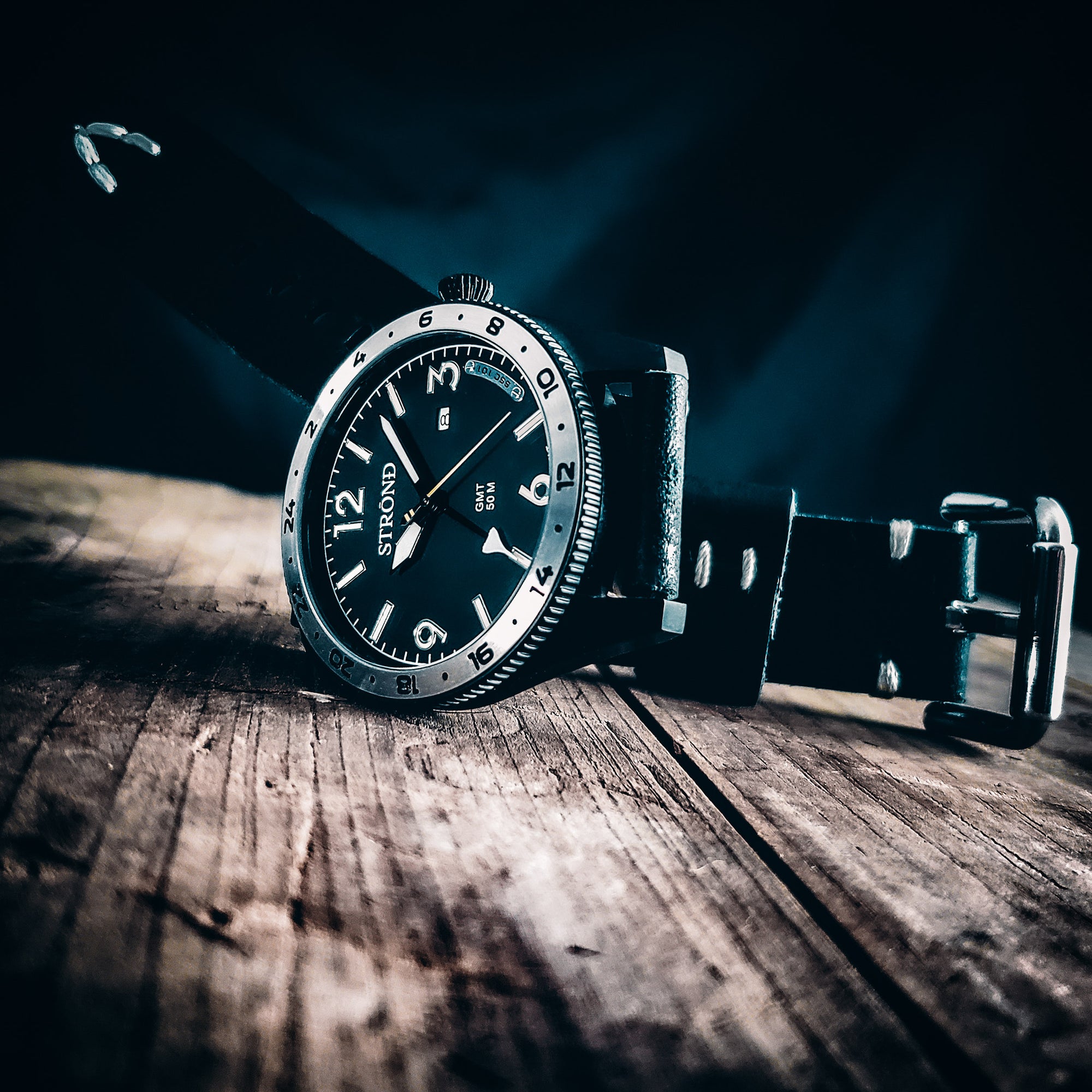 Black wristwatch with leather strap on a wooden surface