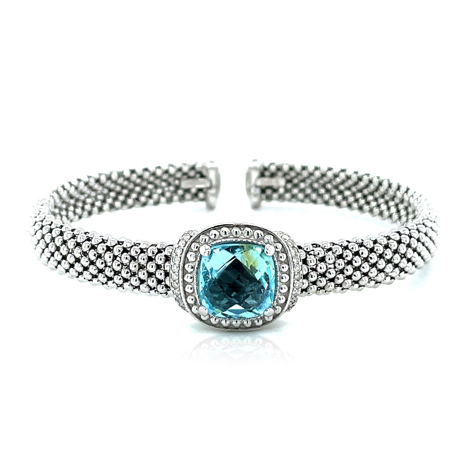 Sterling silver cuff bangle featuring a central blue topaz surrounded by diamonds and textured with a popcorn finish.