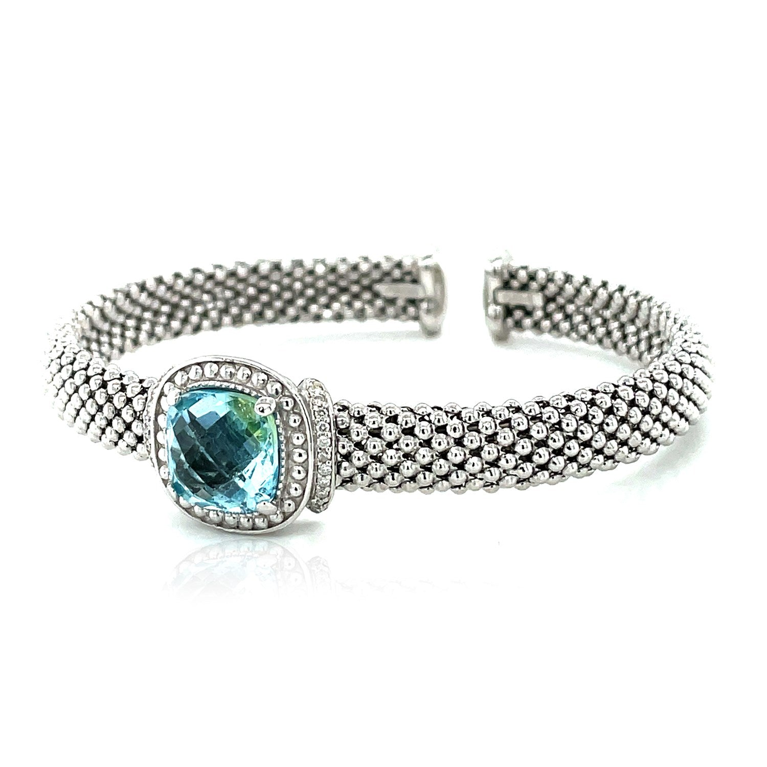 Sterling silver cuff bangle featuring a central blue topaz surrounded by diamonds and textured with a popcorn finish.