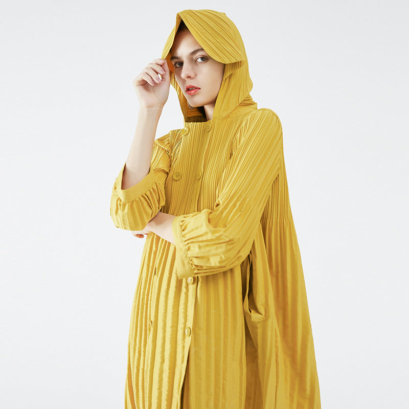Woman wearing a yellow pleated dress with a hood on a white background