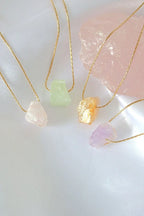 Three necklaces with colorful stone pendants on a light background
