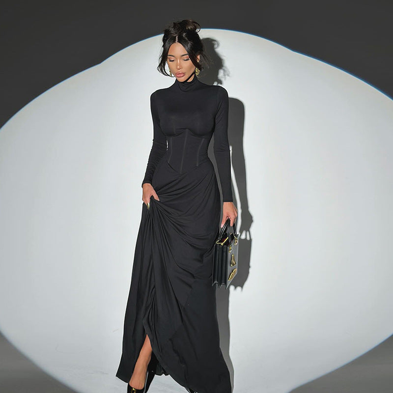 Woman wearing a black dress with a high slit, holding a clutch against a white background.