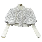 White quilted shrug over a white sweater on a white background