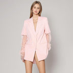 Woman wearing a light pink blazer dress against a plain background