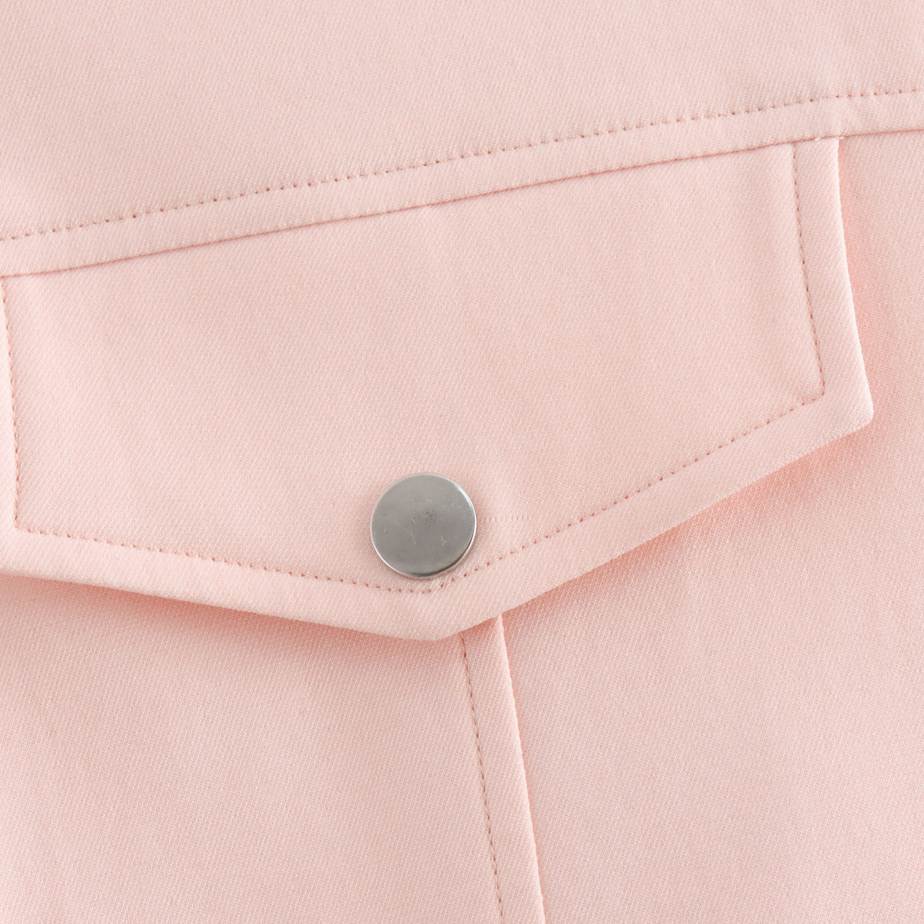 Close-up of a pink fabric with a button on a light pink background