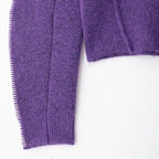Close-up of a purple textured sweater sleeve on a white background
