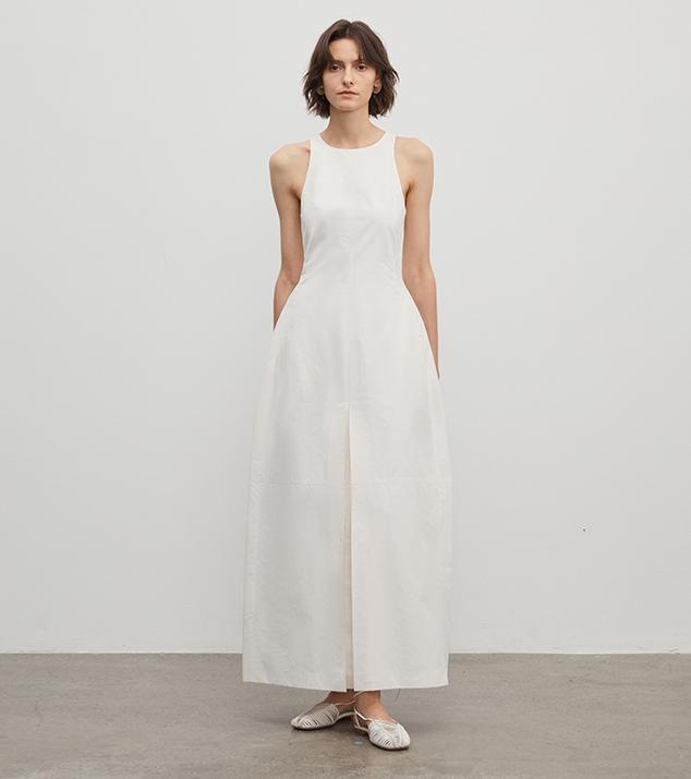 Woman wearing a white sleeveless dress against a plain background