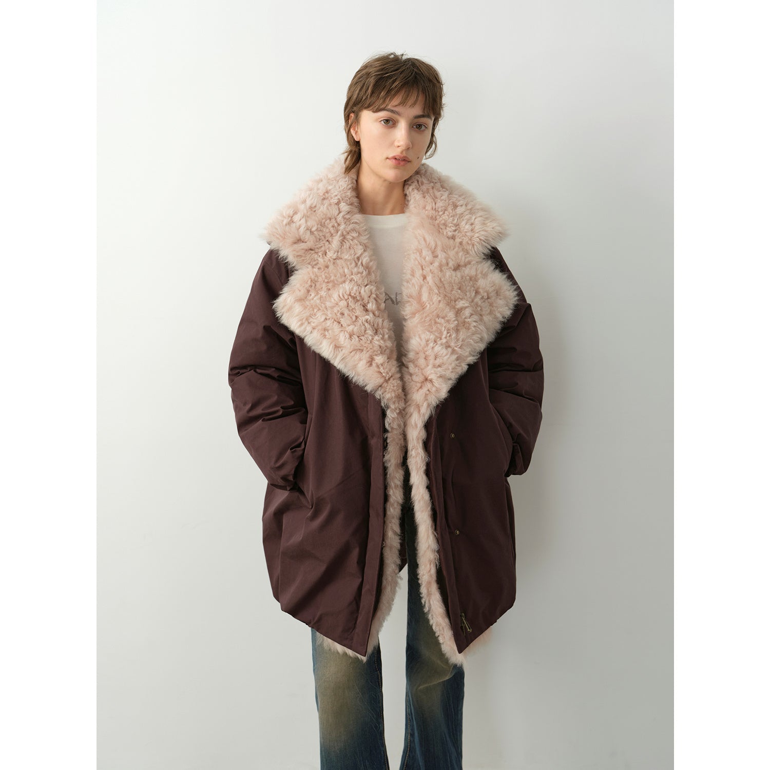 Person wearing a brown coat with a fur collar on a white background