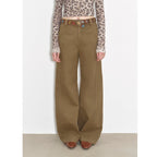 Person wearing brown wide-leg pants with a patterned top on a white background