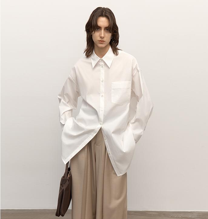 Person wearing an oversized white shirt with a plain background