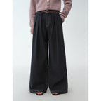 Person wearing black wide-leg pants with a plain background