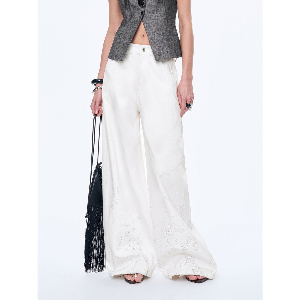 Person wearing white pants and a gray vest holding a black handbag on a white background