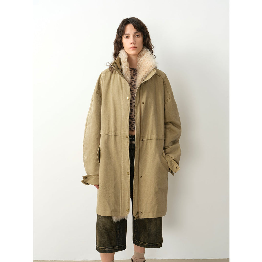 Person wearing a long beige coat with fur trim on a white background