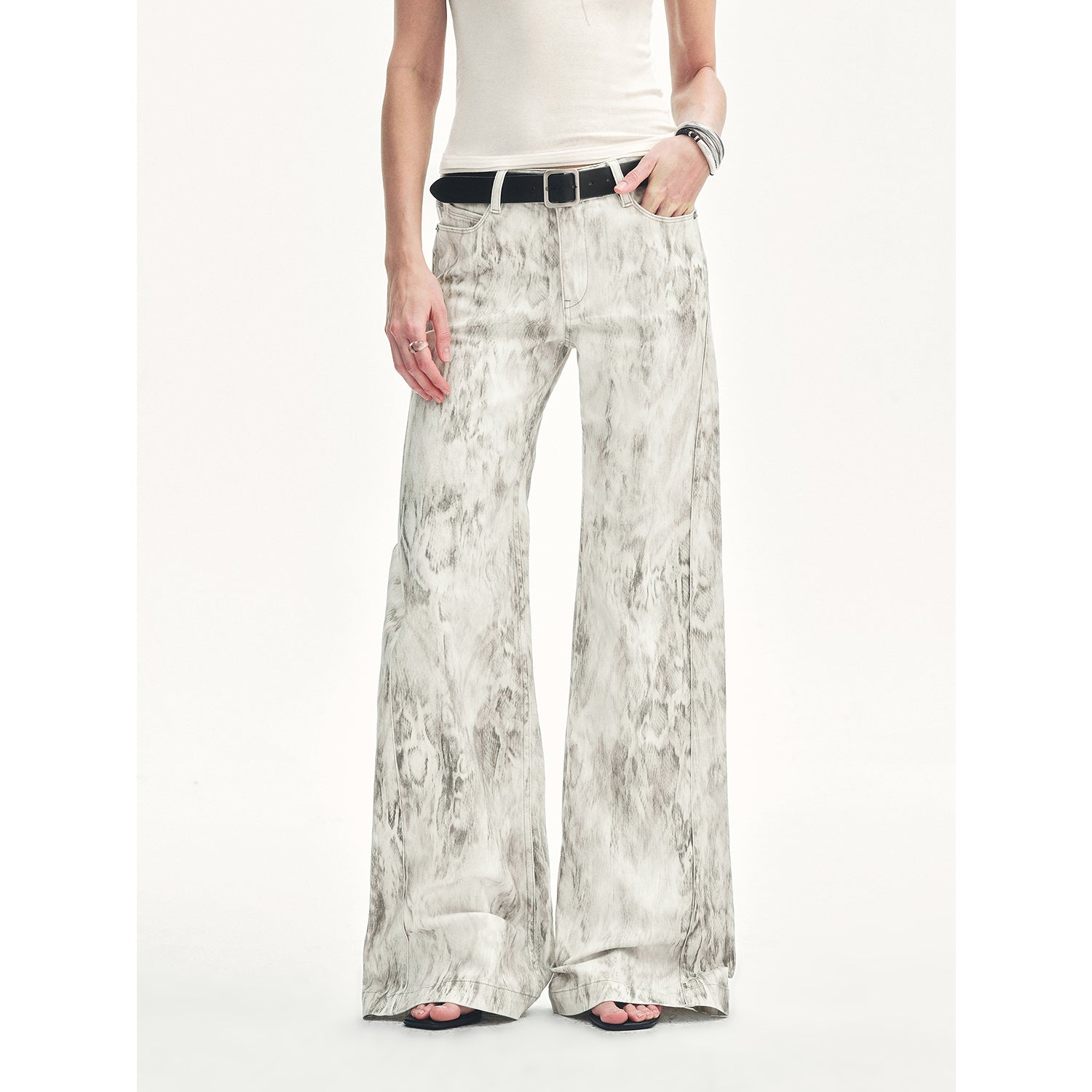Person wearing a white top and patterned wide-leg pants on a white background