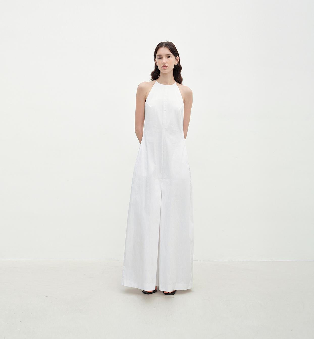 Woman wearing a white halter neck jumpsuit on a plain background