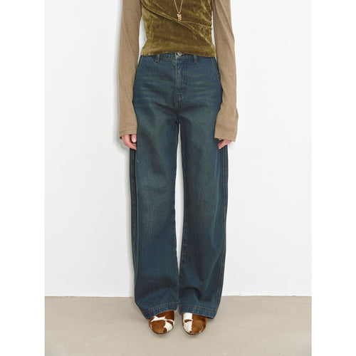 Person wearing blue jeans and a green top against a white background