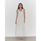 Woman wearing a white sleeveless dress on a plain background