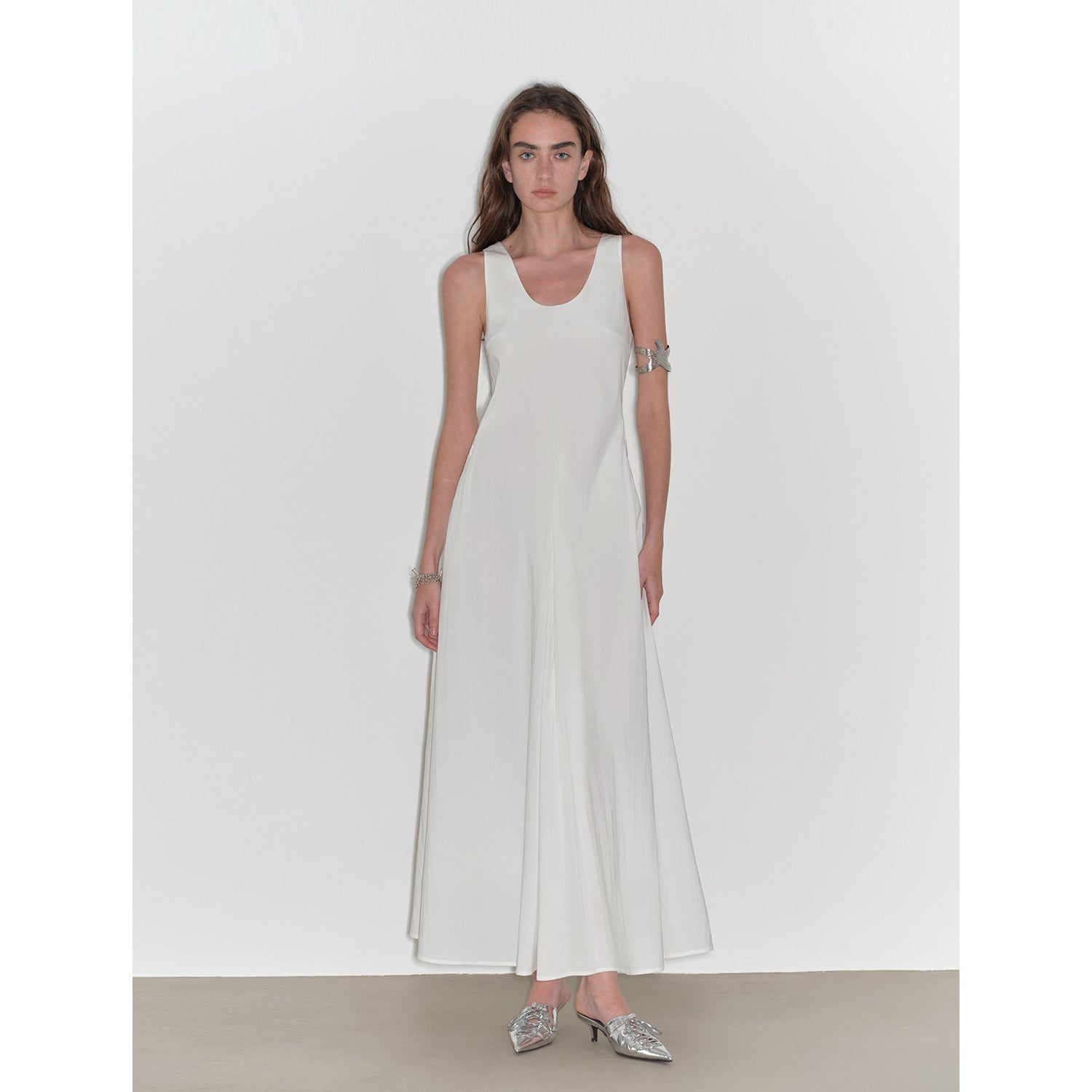 Woman wearing a white sleeveless dress on a plain background