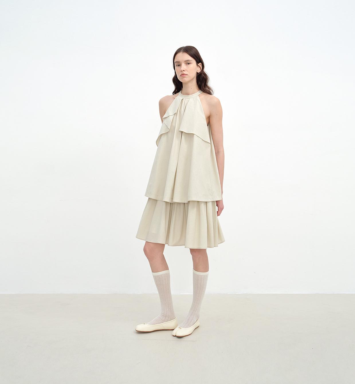 Woman wearing a beige dress with ruffled layers on a white background