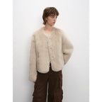 Person wearing a beige fur coat against a white background