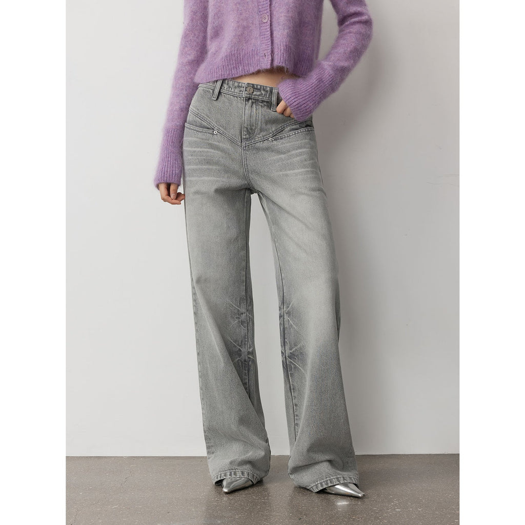 Person wearing gray wide-leg jeans and a purple sweater against a plain background