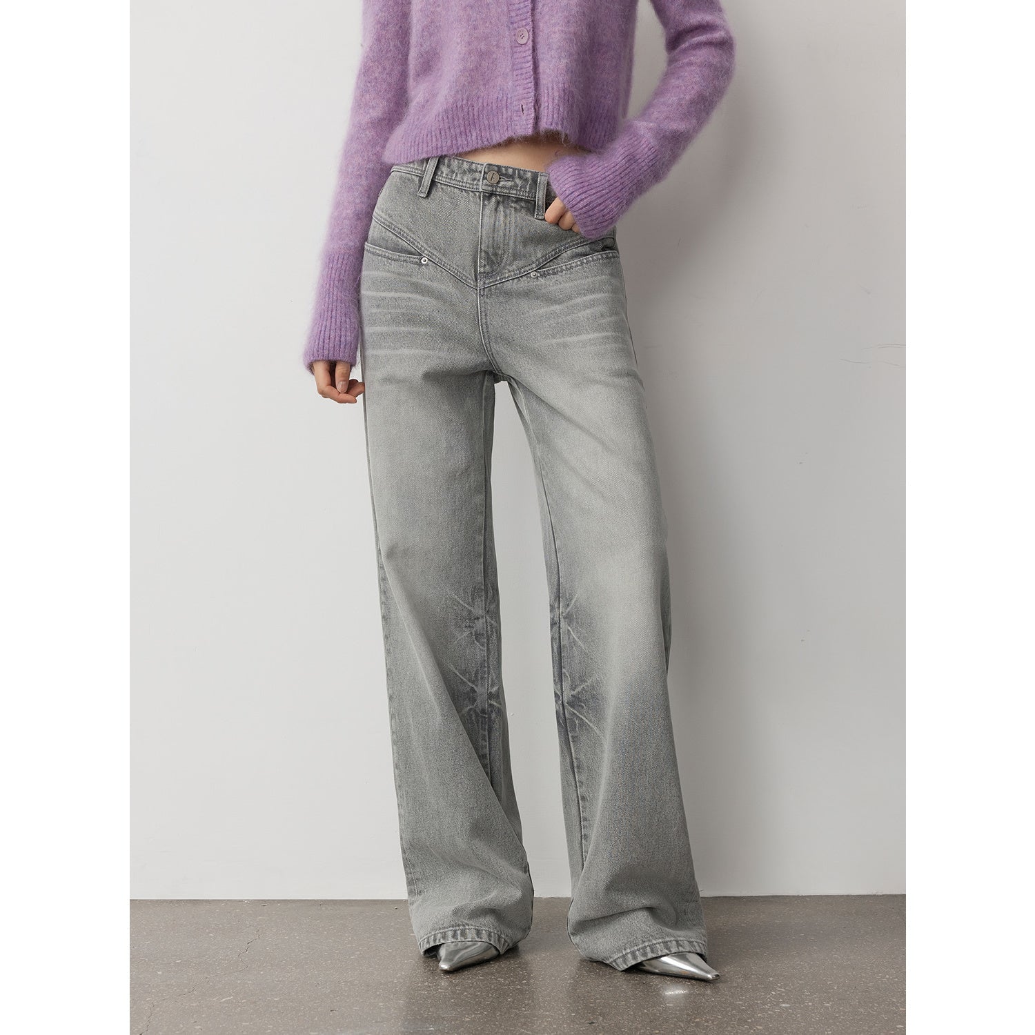 Person wearing gray wide-leg jeans and a purple sweater against a plain background