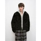 Person wearing a black fluffy jacket and plaid pants on a white background