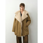 Person wearing a brown coat with a fur-lined hood against a white background