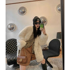 Person taking a mirror selfie wearing a white fur coat, brown skirt, and black boots in a stylish room.