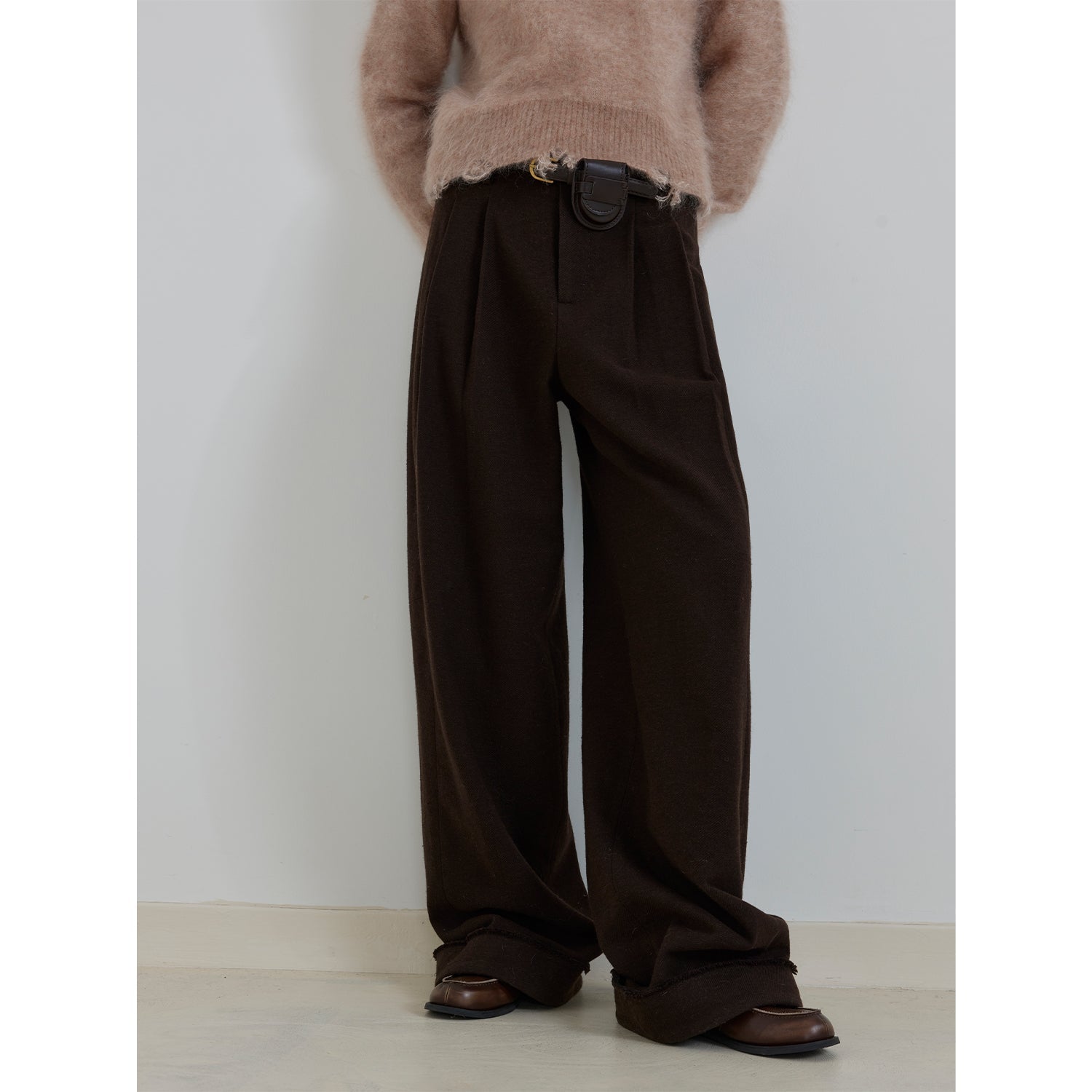 Brown wide-leg pants worn with a beige sweater against a white background